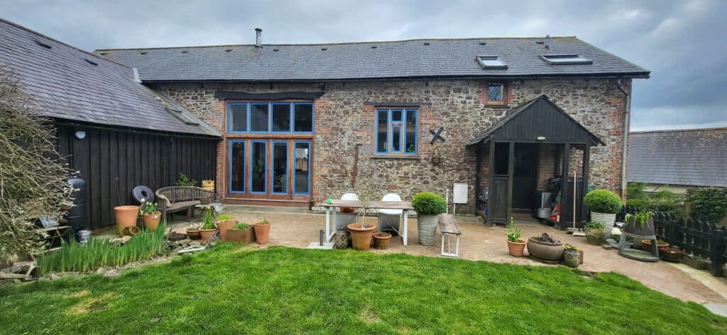 Restored slate-roofed stone barn conversion with timber doors and sash windows — Heritage Specialist work.