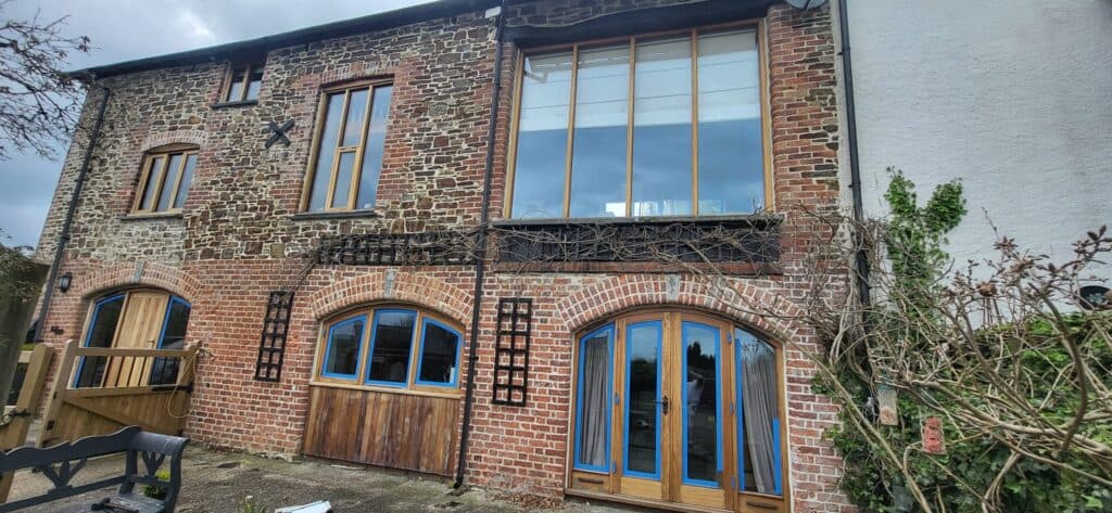 Restored brick and stone heritage cottage with arched timber doors painted blue.
