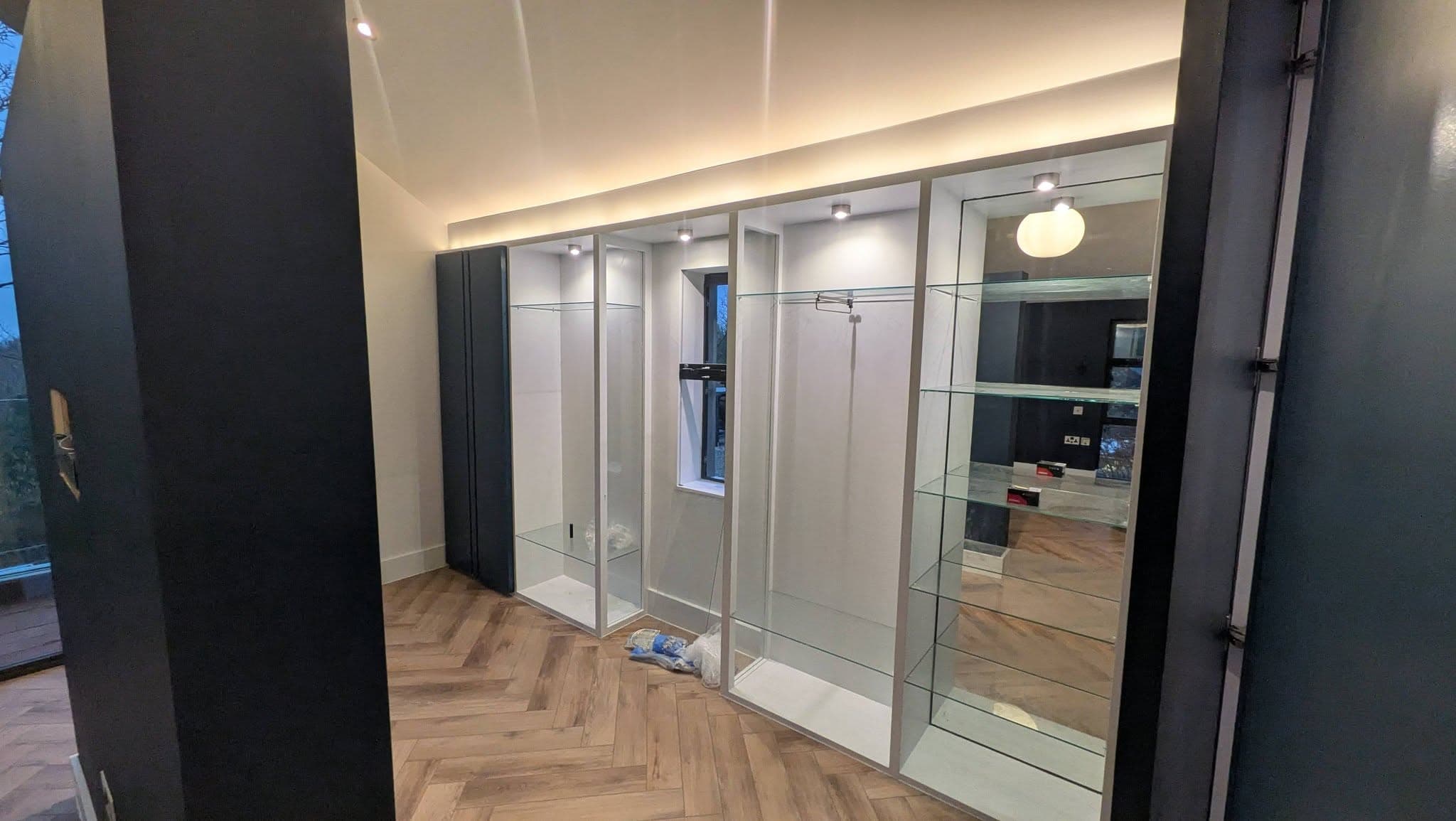Walk-in dressing room with mirrored fitted wardrobes, dark walls and herringbone parquet floor.