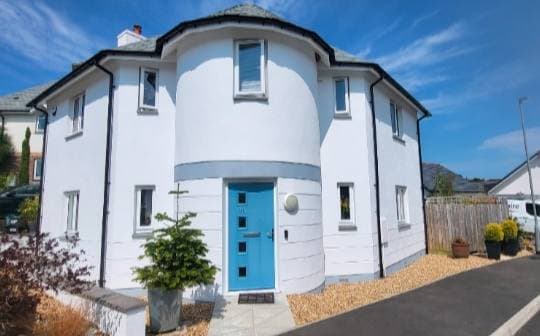 White rendered period cottage with rounded turret bay and bright blue front door, freshly finished.